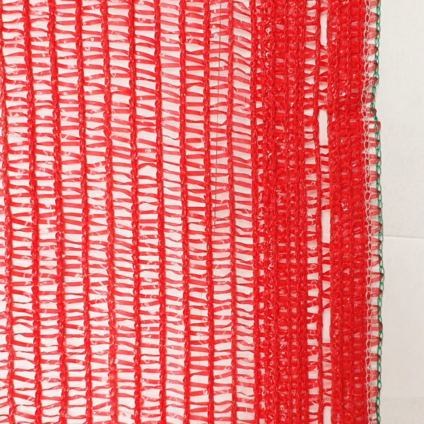 Imagen de una malla sombra fotoselectiva roja, diseñada para proteger cultivos. La malla presenta un tejido de hilos rojos entrelazados con bordes verdes, ideal para filtrar la luz solar y optimizar el crecimiento de las plantas.